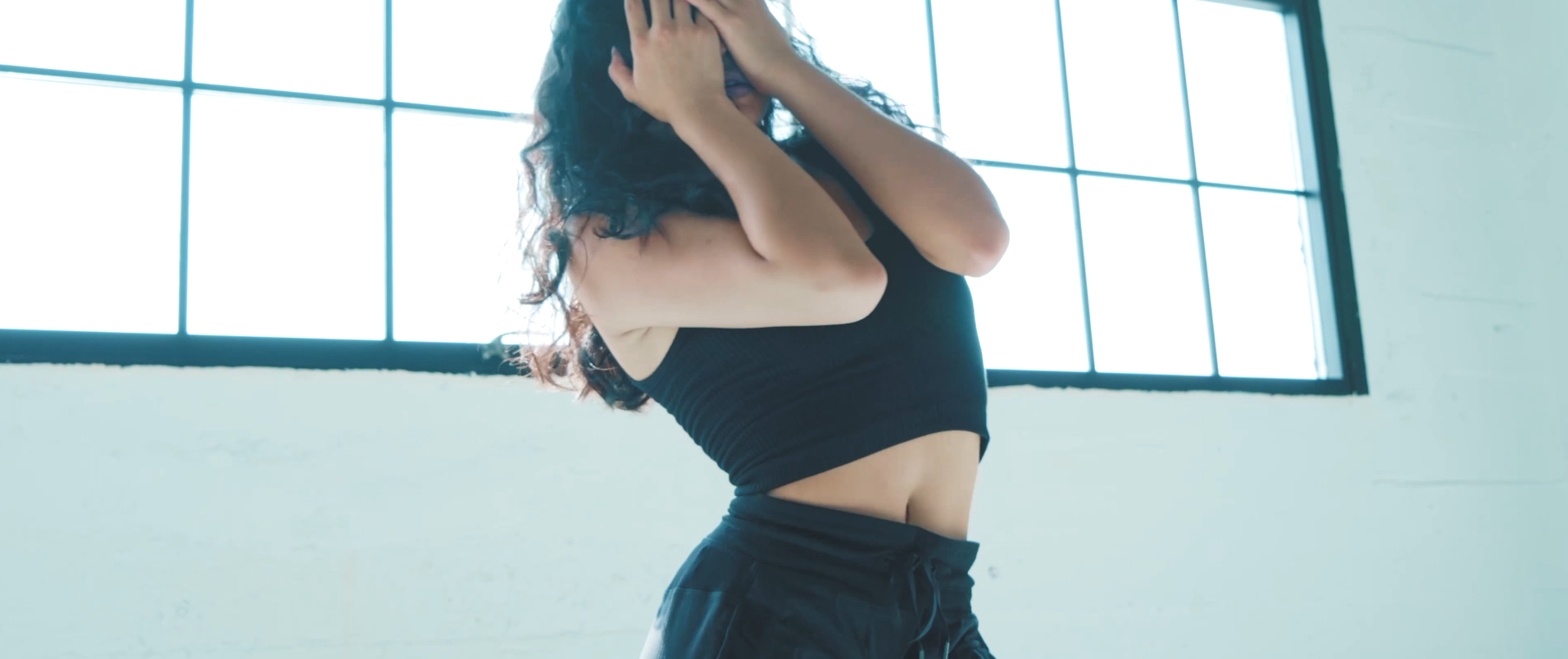 Dancer posed against a bright studio window in a high-key frame