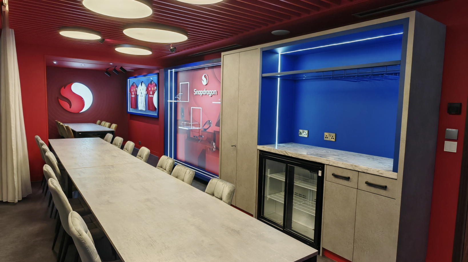 Snapdragon VIP suite at Old Trafford — red interior with jersey display and Snapdragon Fireball