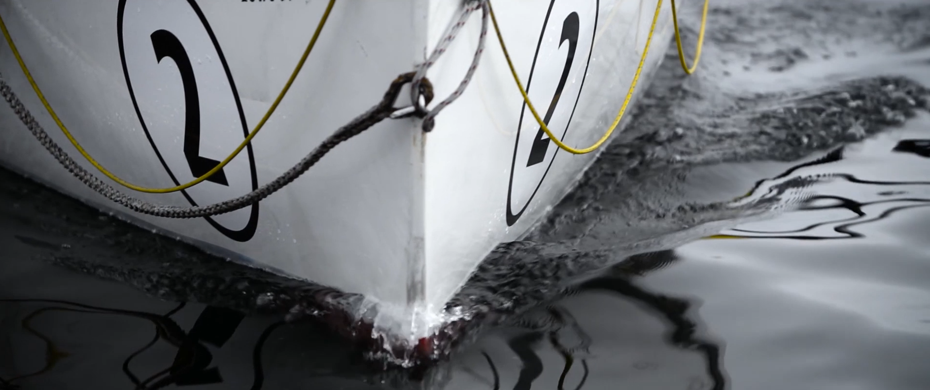 Boat bow cutting through dark reflective water in a documentary frame